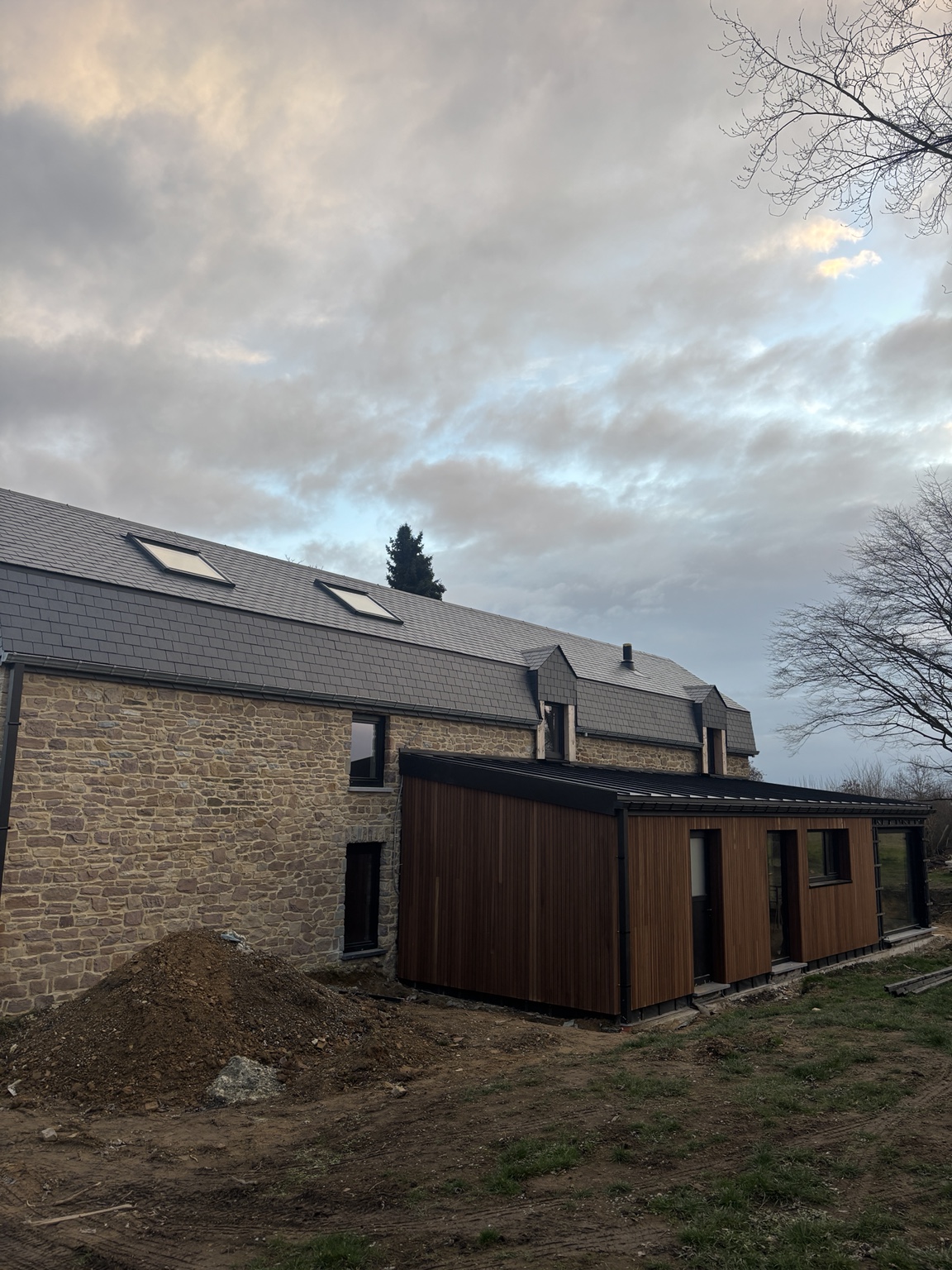 Vue d’ensemble du bâtiment en pierre et de son annexe habillée de bois